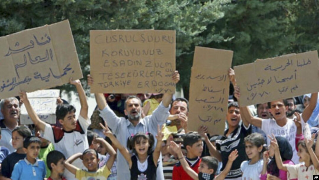 Syrian refugees hold banners - second from left reads 'Protect Jisr al-Shughour from Bashar al-Assad. Thanks to Turkey-Erdogan' - and chant slogans at Altinozu refugee camp in the Turkish border town of Altinozu in Hatay province, June 10, 2011