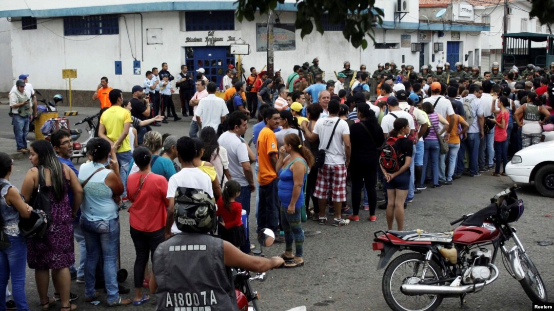 FILE - People make a line in front of Venezuelan National Guards as they wait to try to cross the border to Colombia over the Francisco de Paula Santander international bridge in Urena, Venezuela, Dec. 18, 2016.