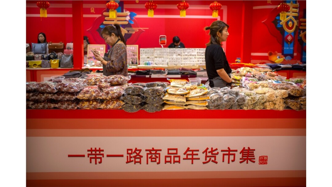 FILE - Clerks stand at a display of goods at a Belt and Road Products New Year's Marketplace at a shopping mall in Beijing, Jan. 10, 2020. The market showcases products created from countries and regions involved in China's Belt and Road Initiative.