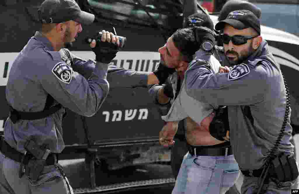 An Israeli policeman films a Palestinian as others hold him for detention during a demonstration at the Palestinian Bedouin village of Khan al-Ahmar, east of Jerusalem in the occupied West Bank and which Israel plans to demolish.