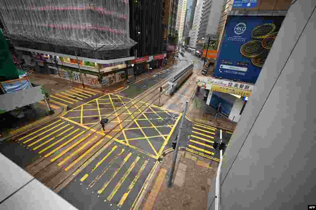 A pedestrian crosses an empty street in the Central business district as Hong Kong battens down for the second time in less than a week as Tropical Cyclone Kompasu prompted forecasters to raise their alert level and usher in mandatory safety measures.