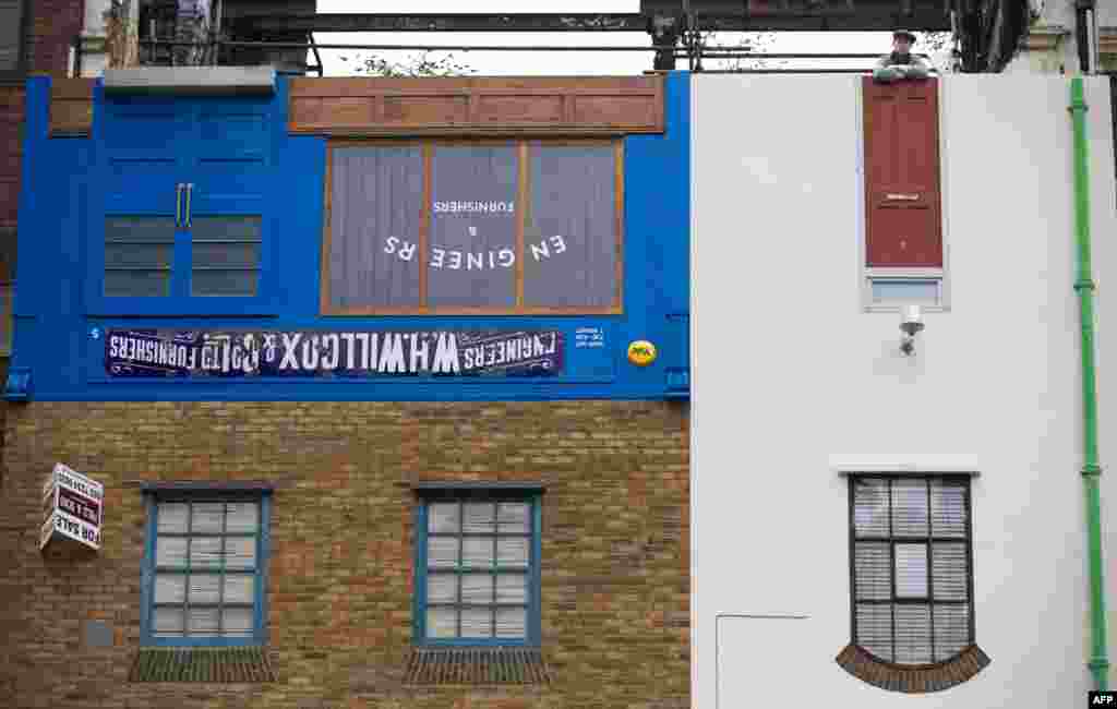 Artist Alex Chinneck poses on the rooftop of his latest art installation Miner on the Moon (Upside Down House) upon its unveiling on Blackfriars Road in Central London.