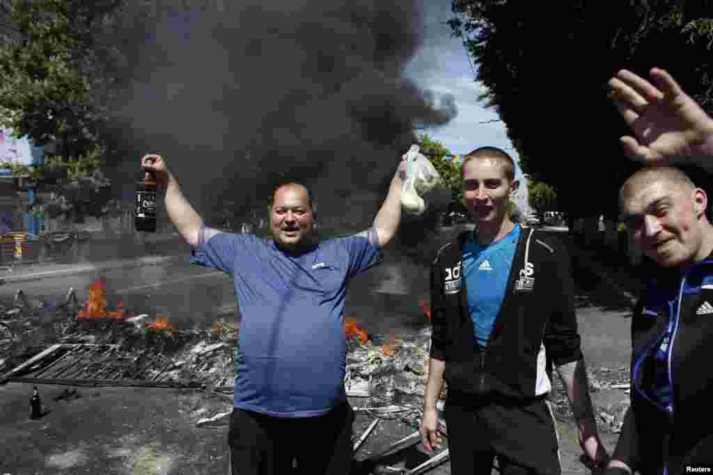 People react as they stand in front of a burning barricade near the city hall in Mariupol, eastern Ukraine, May 10, 2014.