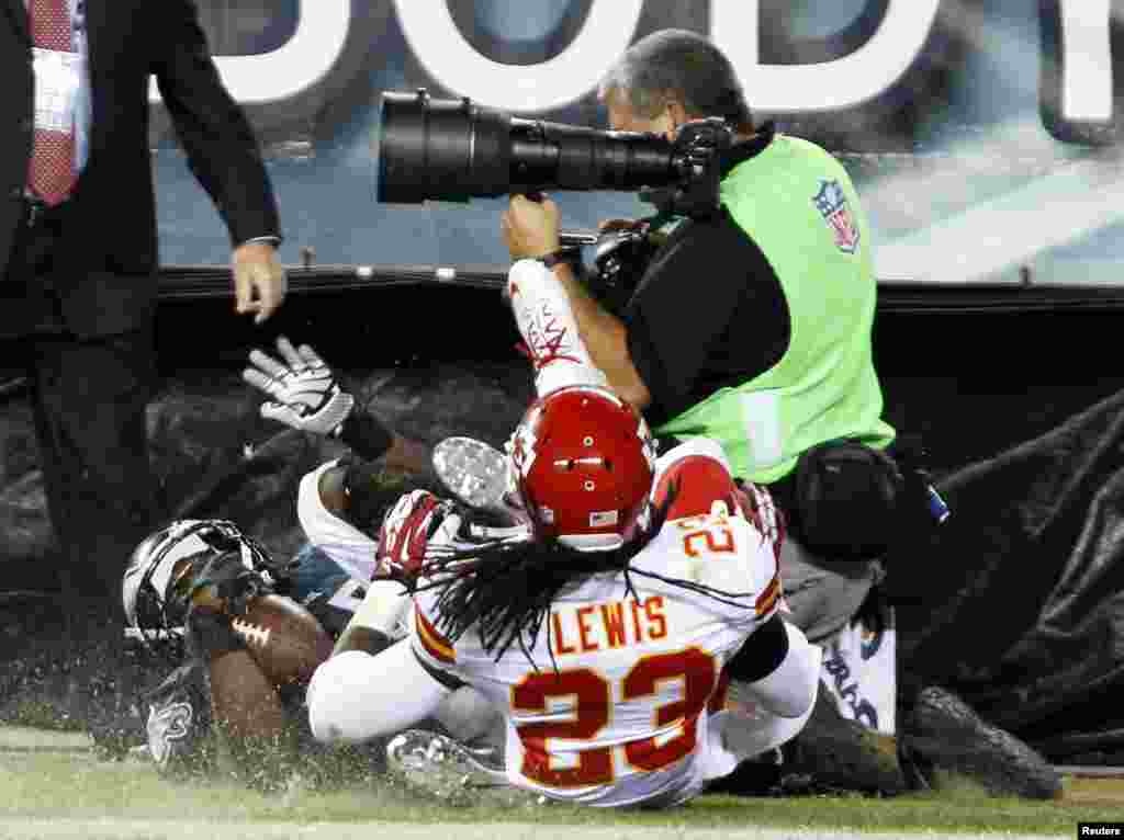 Philadelphia Eagles' LeSean McCoy (25) and Kansas City Chiefs' Kendrick Lewis (23) roll into a photographer on the sidelines after McCoy scored a touchdown during the fourth quarter of the NFL football game in Philadelphia, Pennsylvania, Sept. 19, 2013.