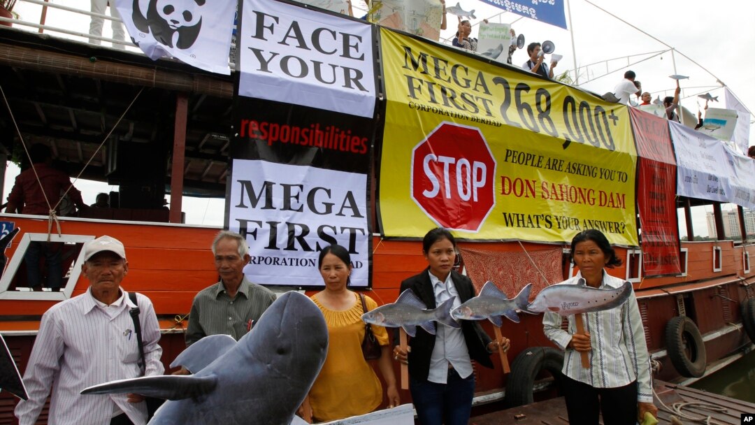 FILE - Cambodian non-governmental organization (NGOs) activists hold a cut-out of Mekong dolphin, left, and cut-out of other species during a protest against a proposed Don Sahong dam, in Phnom Penh, Cambodia, Sept. 11, 2014. 