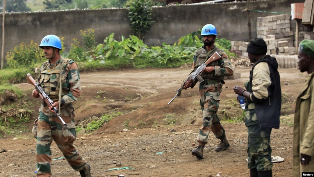 U.N. peacekeepers walk past rebel soldiers in Bunagana, July 7, 2012. 