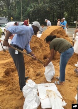 El alcalde de Tallahassee y candidato a la gobernación de Florida, Andrew Gillum, (izquierda) ayuda a Eboni Sipling a llenar bolsas de arena en Tallahassee, Florida, el lunes, 8 de octubre de 2018.