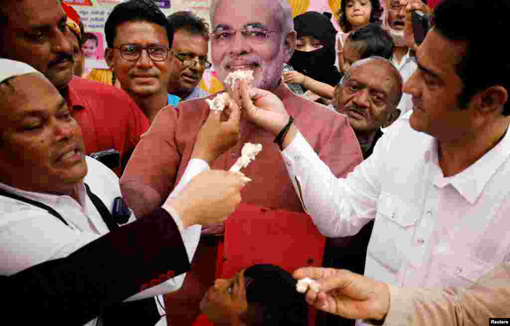 People offer pieces of a cake to a cut-out of India's Prime Minister Narendra Modi as they celebrate his 71st birthday at an event in Ahmedabad, India.