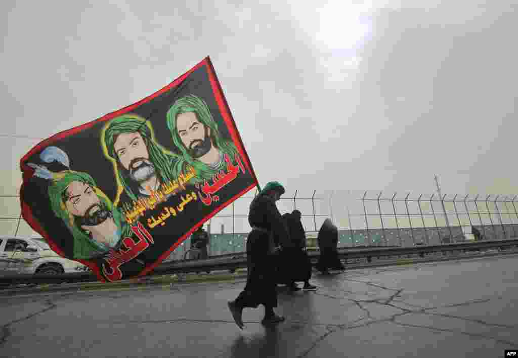 A Shiite Muslim pilgrim carries a flag depicting the Prophet Mohammed's cousin Ali ibn Abi Taleb and his two sons on the outskirts of Baghdad on the way to the holy Iraqi city of Karbala.