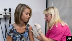 FILE - Lauren Fant, left, winces as she has the human papillomavirus (HPV) vaccine administered by nurse Stephanie Pearson at a doctor's office in Marietta, Ga., Dec. 18, 2007. 