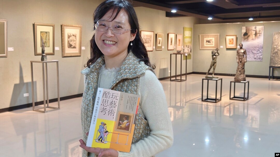 In this photo taken on March 23, 2021, Taiwanese author Iris Chiang holds her book "Play with Art" at an event featuring Taiwanese artist YUYU Yang's work in Taipei, Taiwan. (AP Photo/Chiang Ying-ying)