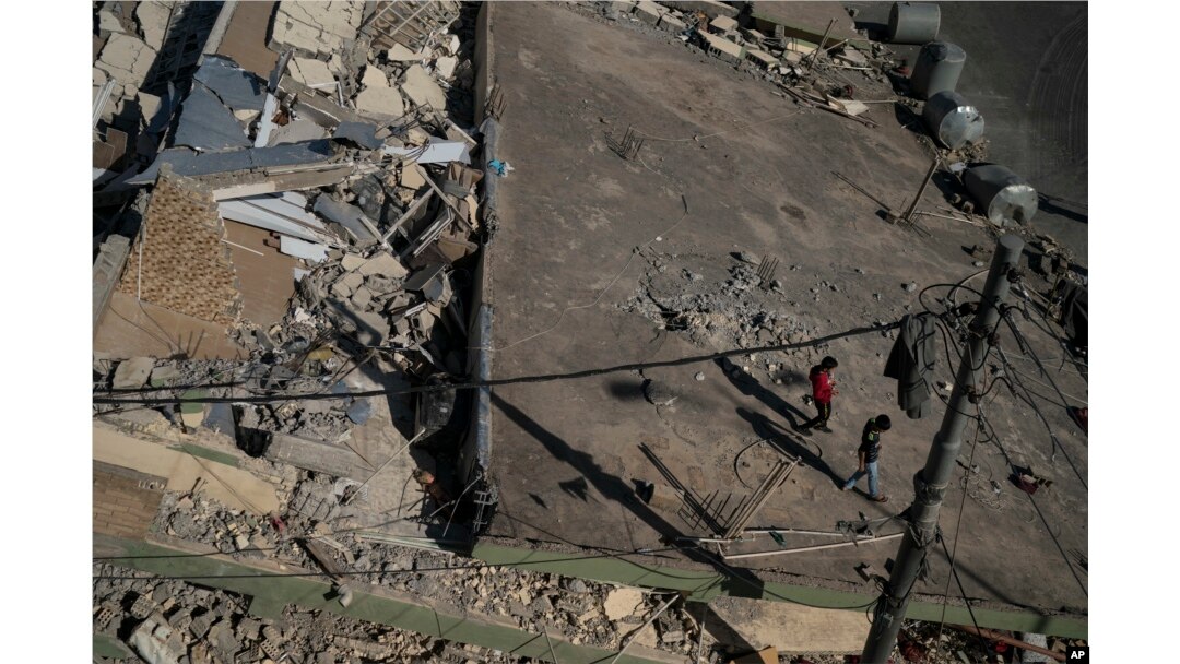 Boys walk on the roof of a destroyed house after an earthquake in the city of Darbandikhan, northern Iraq, Nov. 13, 2017.