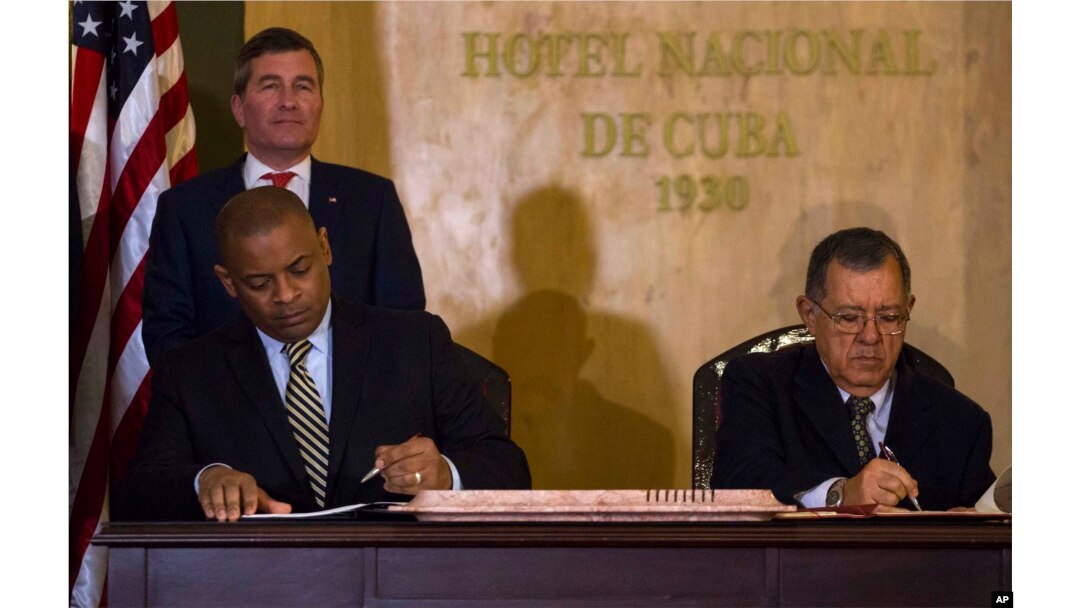 U.S.Transportation Secretary Anthony Foxx and Cuba's Minister of Transportation Adel Yzquierdo Rodriguez, right, sign the airline transportation agreement as Assistant Secretary of State for Economic and Business Affairs Charles Rivkin, top left, looks on in Havana, Cuba, Feb. 16, 2016.