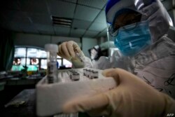 En esta foto tomada el 10 de marzo de 2020, se ve a personal médico sosteniendo muestras de pacientes infectados con el nuevo coronavirus en un hospital de la Cruz Roja en Wuhan, China.