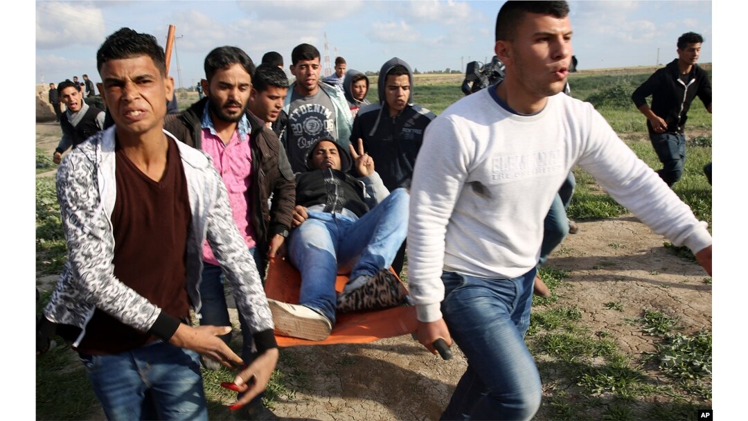 Palestinian protesters evacuate a wounded person during clashes with Israeli troops on the Israeli border with Gaza, east of Gaza City, March 16, 2018.