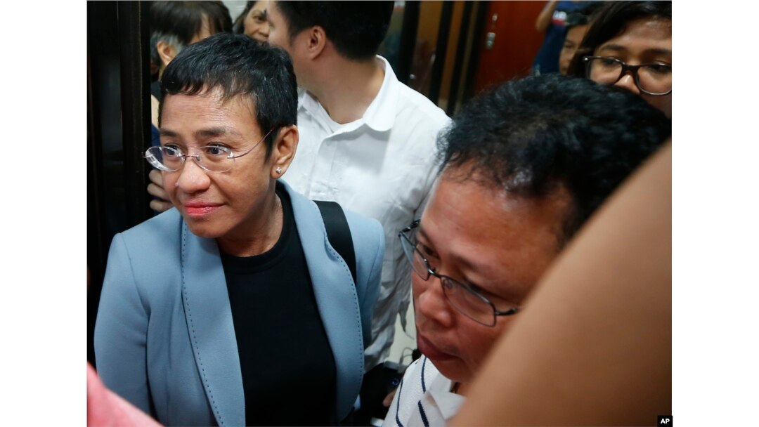 Maria Ressa, the award-winning head of a Philippine online news site Rappler that has aggressively covered President Rodrigo Duterte's policies, is escorted into another room following her arrest by National Bureau of Investigation agents in a libel case,
