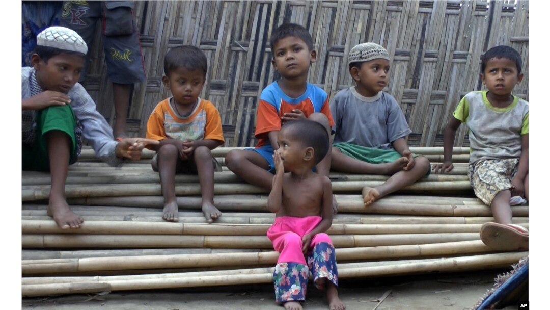 FILE - In this March 17, 2017, image made from video, Rosmaida Bibi, center foreground, suffering from severe malnutrition, sits on a pile of bamboo trees with other children at the Dar Paing camp, north of Sittwe, Rakhine state, Myanmar.
