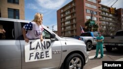 Trabajadores de la salud interrumpen los vehículos de manifestates que pedían el levantamiento de las restricciones por el coronavirus en Denver, Colorado, el 19 de abril de 2020.
