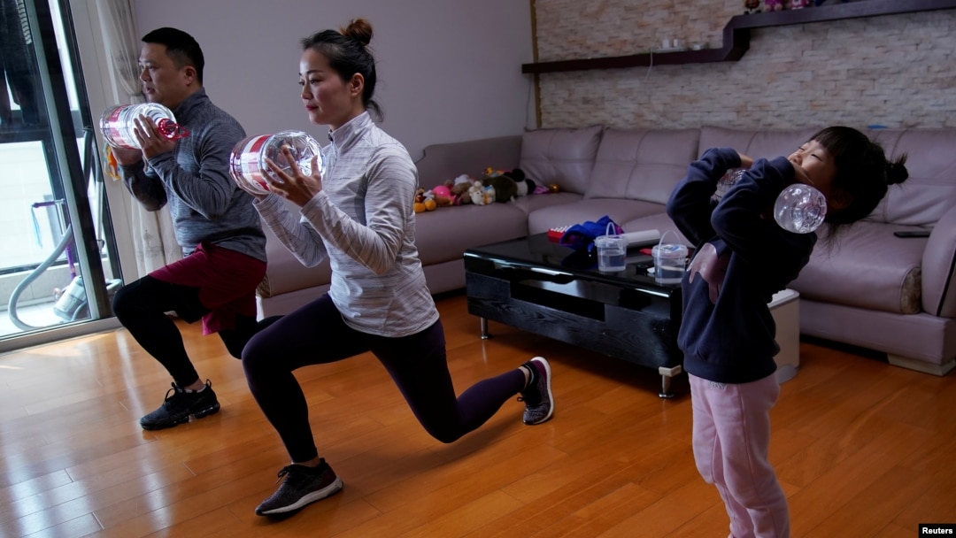 Dino Lin, Stella Zhang and Wowo Lin, 5, exercise using filled water bottles as weights as they watch a fitness class online at their house, during the novel coronavirus disease (COVID-19) outbreak, in Shanghai, China, February 25, 2020. 
