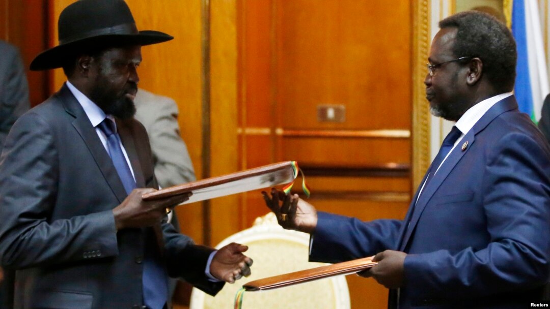 FILE - South Sudan's President Salva Kiir (L) and the country's rebel leader, Riek Machar, exchange signed peace agreement documents in Addis Ababa May 9, 2014.