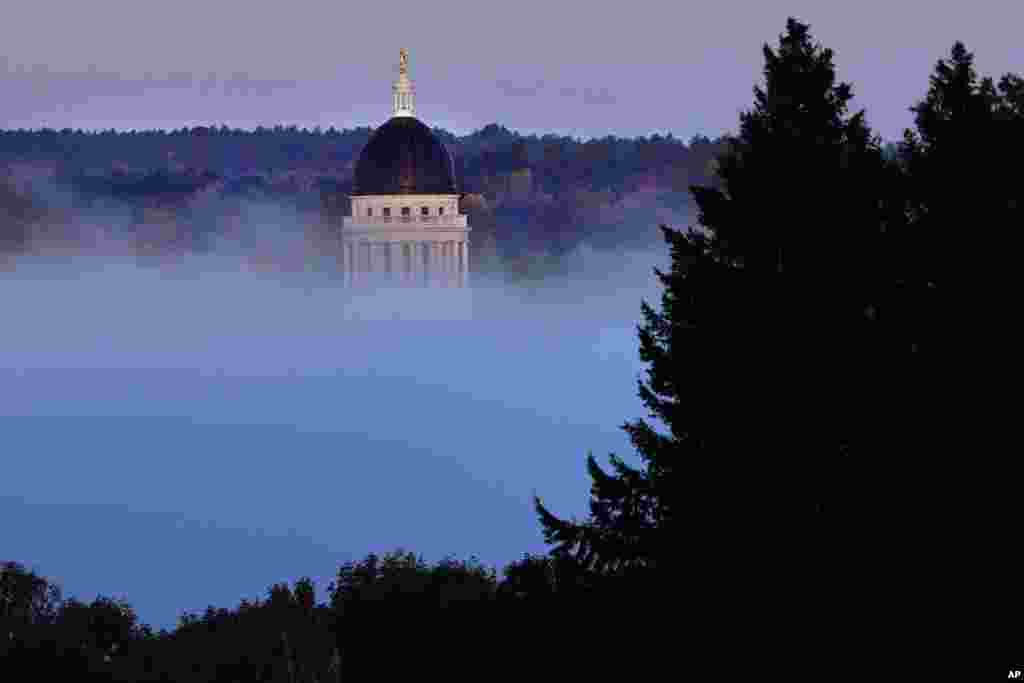 The Maine State House can be seen above the fog rising from the banks of the Kennebec River on a chilly morning in Augusta.