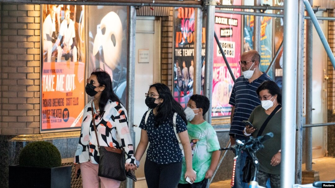 Masked people walk past posters advertising theater shows as the U.S. registers a surge in infections with the highly transmissible delta variant of the coronavirus, in New York City, July 30, 2021.