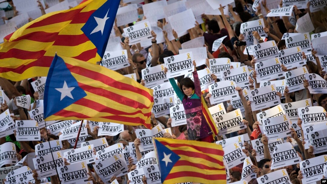 Protesters hold signs reading 'Freedom for the two Jordis' during a march to protest against the National Court's decision to imprison civil society leaders, in Barcelona, Oct. 21, 2017. 