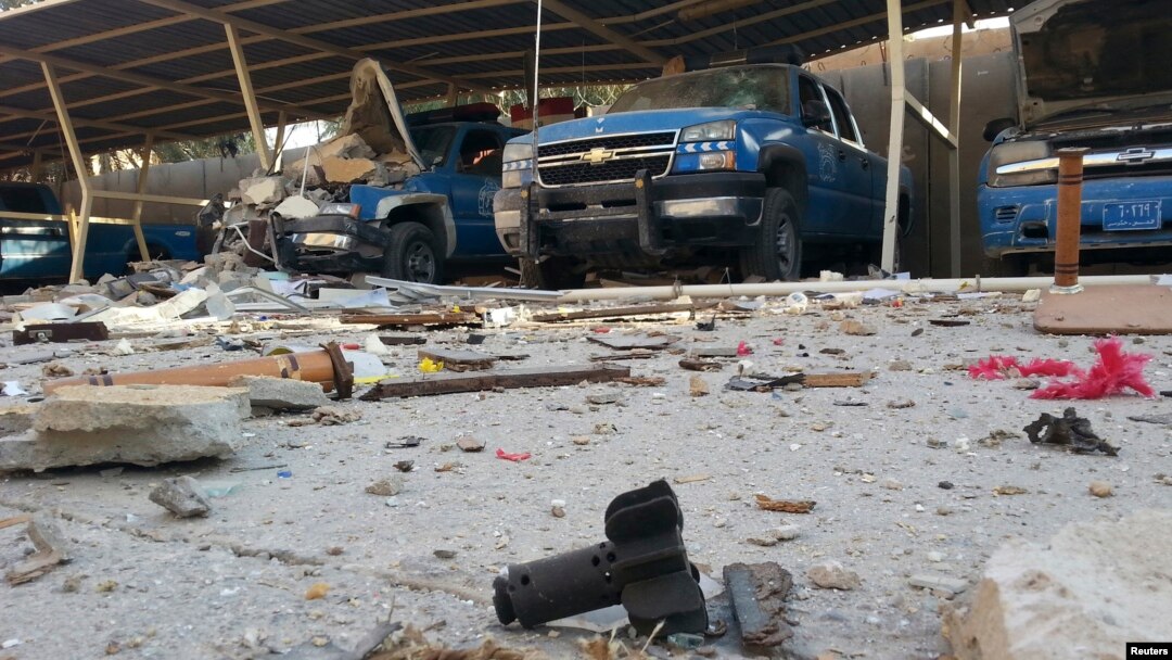 Police vehicles are parked next to debris in the Anbar province town of Hit, Iraq, Oct. 6, 2014. 