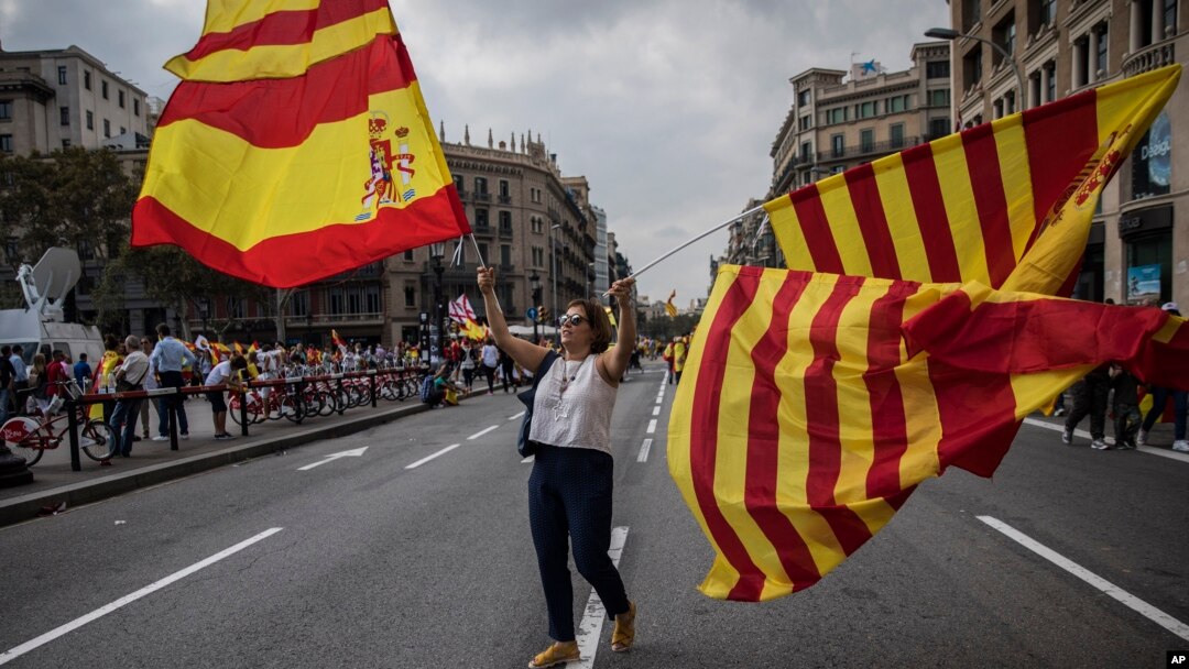 A woman waves flags of Catalonia and Spain as people celebrate a holiday known as "Dia de la Hispanidad" or Spain's National Day in Barcelona, Spain, Oct. 12, 2017. 