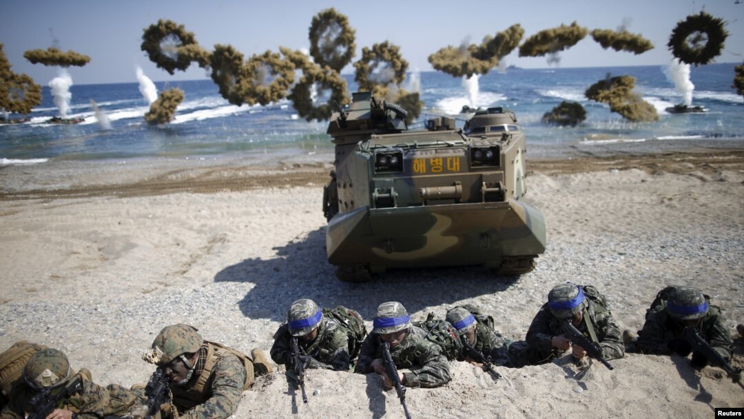 FILE - South Korean (blue headbands) and U.S. Marines take positions as amphibious assault vehicles of the South Korean Marine Corps fire smoke bombs during a U.S.-South Korea joint landing operation drill in Pohang, South Korea, March 12, 2016. 