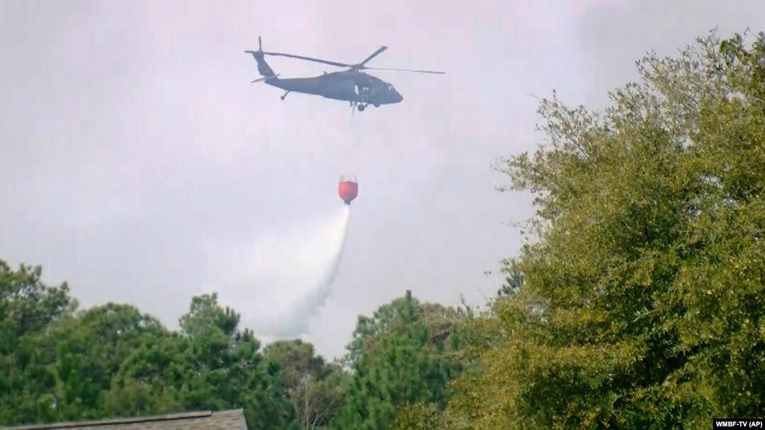 A helicopter drops water to help contain a fire in the Carolina Forest area west of the coastal resort city of Myrtle Beach, South Carolina, March 2, 2025, where residents were ordered to evacuate several neighborhoods. 
