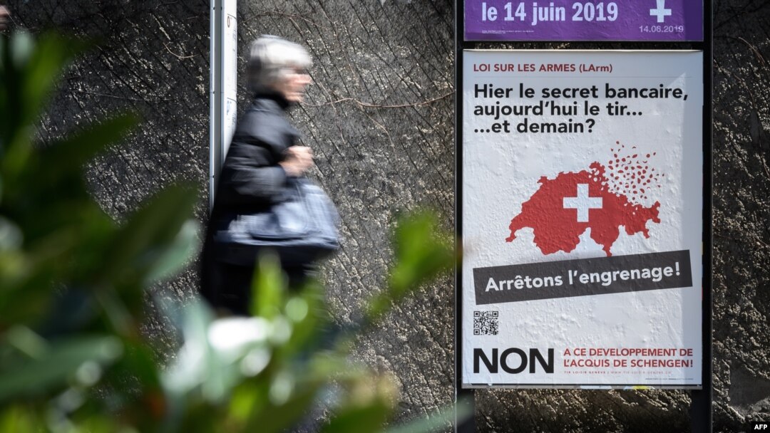 A woman walks past a campaign poster against toughening gun laws in Switzerland. It reads in French, "Yesterday banking secrecy, today shooting ... and tomorrow? Let's stop the spiral!" May 13, 2019, in Geneva.