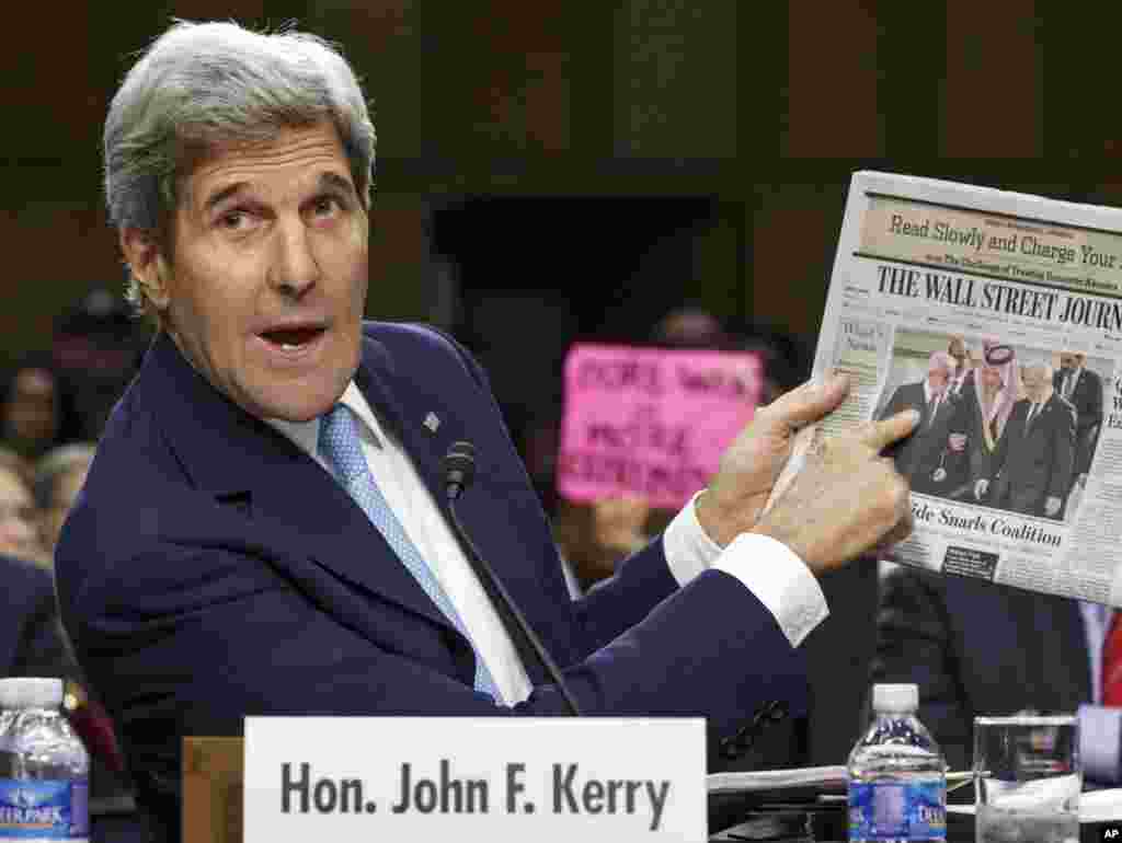 Secretary of State John Kerry points to a newspaper photo of the recent Arab summit in Saudi Arabia as an example of the kind of coalition he expects in combating Islamic State extremists in Iraq and Syria, on Capitol Hill in Washington, Sept. 17, 2014.