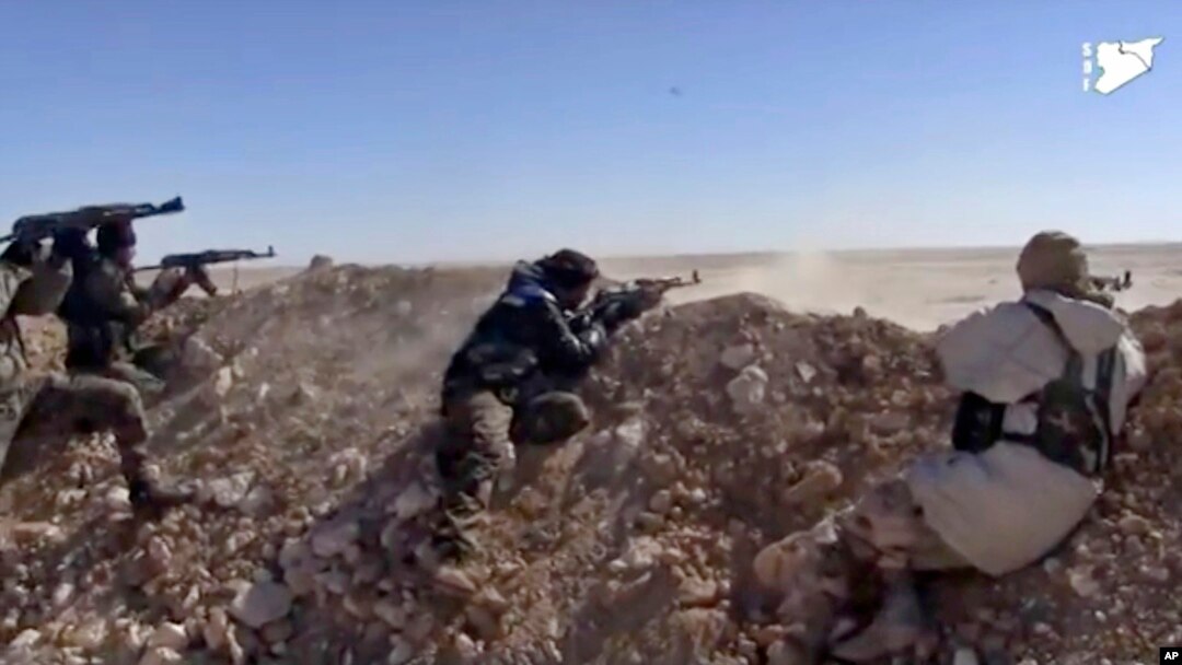 FILE - This frame grab from a video provided by the Syria Democratic Forces (SDF), shows fighters from the SDF opening fire on an Islamic State group's position, in Raqqa's eastern countryside, Syria, March 6, 2017.