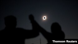 People react while observing a solar eclipse at Incahuasi, a mountain in Chile, July 2, 2019. 