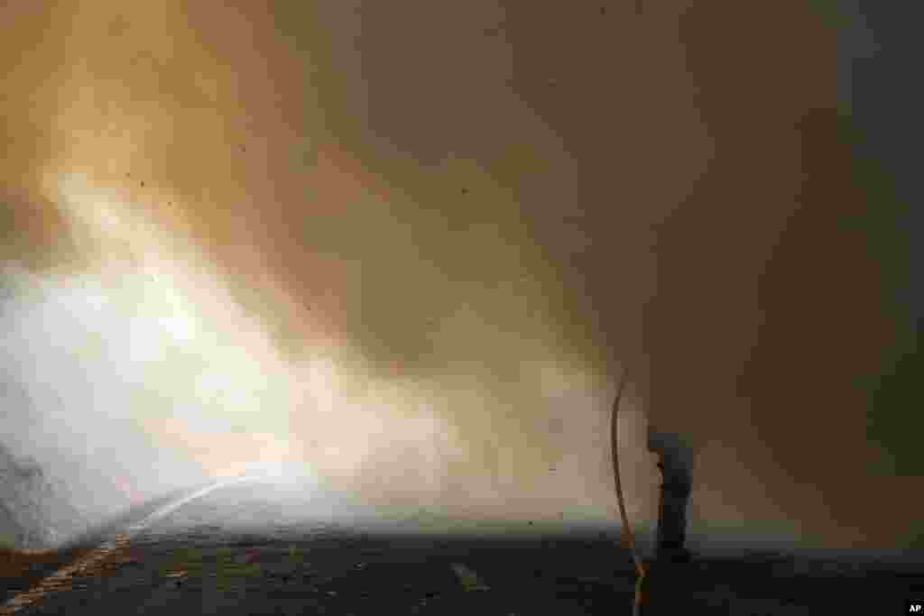 A Portuguese firefighter, surrounded by smoke, uses a hose to fight against a wildfire in Caramulo, north Portugal, Aug. 30, 2013. Portugal asked other European countries to send two more water-dropping aircraft as wildfires continue to scorch areas of forest.