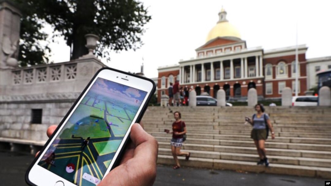 FILE - A Pokemon Go player consults his phone while walking through the Boston Common outside the Massachusetts Statehouse. The game has introduced players to some aspects of history they otherwise might have missed.