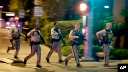 FILE - Police run toward the scene of a shooting near the Mandalay Bay resort and casino on the Las Vegas Strip in Las Vegas, Oct. 1, 2017.