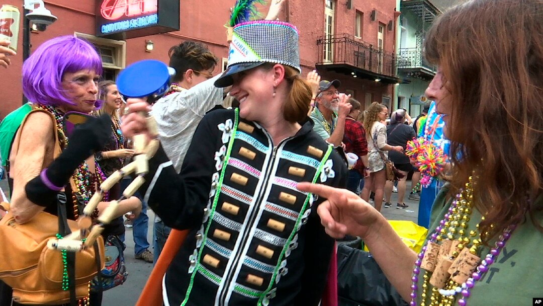 FILE - Image made from video shows a woman wearing a marching band costume taunts revelers with trinkets and beads in the Krewe of Cork parade in New Orleans, Feb. 22, 2019. 
