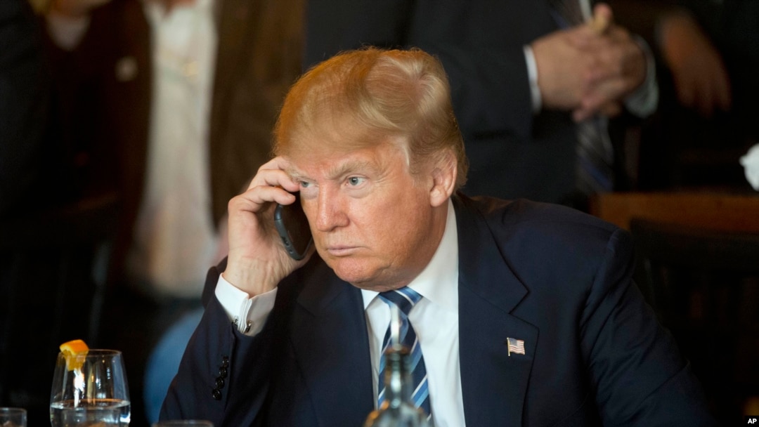 Republican presidential candidate Donald Trump listens to his mobile phone during a lunch stop in North Charleston, S.C., Feb. 18, 2016. Trump tweeted that he now uses government phones. 