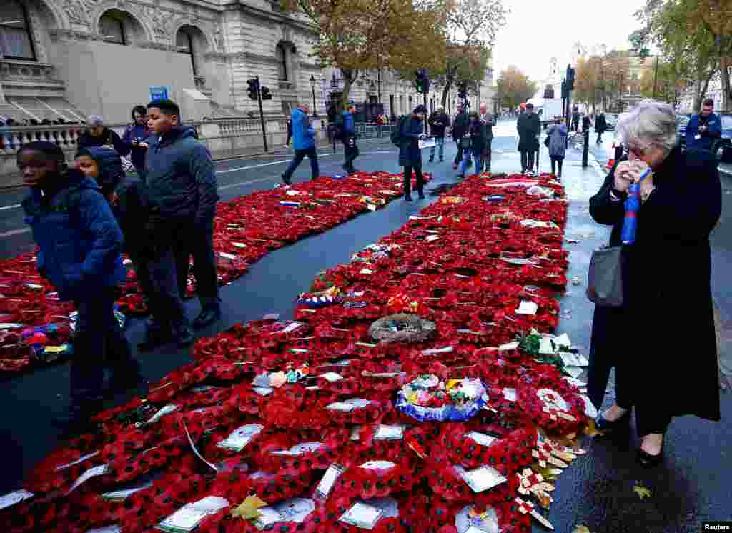 People look at poppy wreaths left around the Cenotaph after yesterday's remembrance ceremonies to mark the centenary of the end of World War 1, in London, Britain.