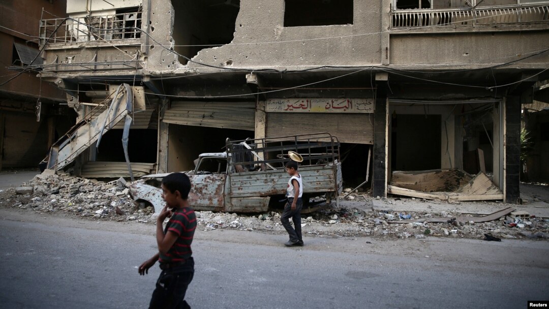 Children walk near damaged buildings in rebel-held Ain Tarma, eastern Damascus suburb of Ghouta, Syria, September 17, 2016.