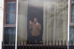 Zari Tadayon gestures from a window of the Radisson Blu Hotel at Heathrow Airport, as Britain introduces hotel quarantine programme for arrivals from a 'red list' of 30 countries, in London, Britain, Feb. 15, 2021.