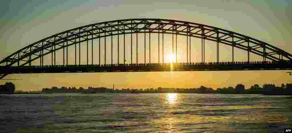 Participants cross a bridge over the Waal River during the first day of the 100th edition of the annual four-day march of Nijmegen, in the Netherlands.