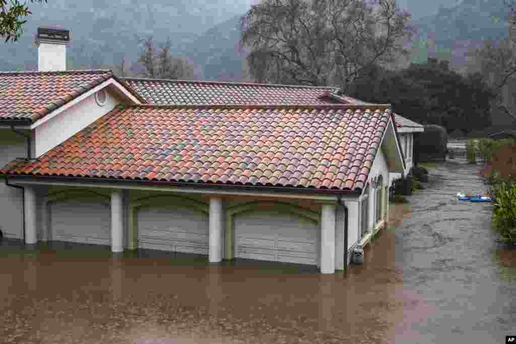 A garage is flooded by the overflowing Carmel River on Paso Hondo Road in Carmel Valley, Jan. 9, 2023. The National Weather Service warned of a “relentless parade of atmospheric rivers” — long plumes of moisture stretching out into the Pacific that can drop staggering amounts of rain and snow.