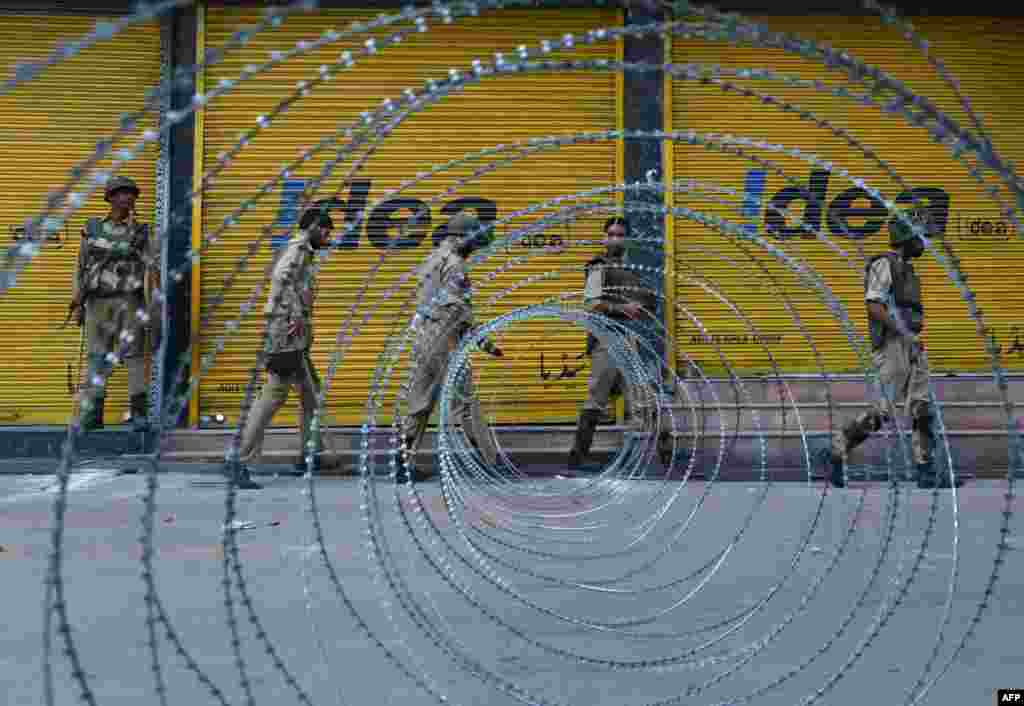 Indian paramilitary and police patrol near a barbed wire fence during a curfew imposed on the Kashmiri summer capital in Srinagar. Indian-administered Kashmir's main city was under curfew after Indian paramilitary forces on Thursday shot dead six people protesting at a raid by troops on an Islamic school.