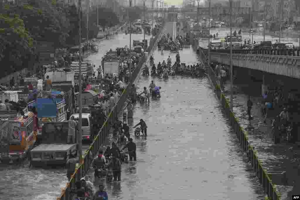 Commuters cross a flooded street after a heavy rainfall in Karachi, Pakistan.