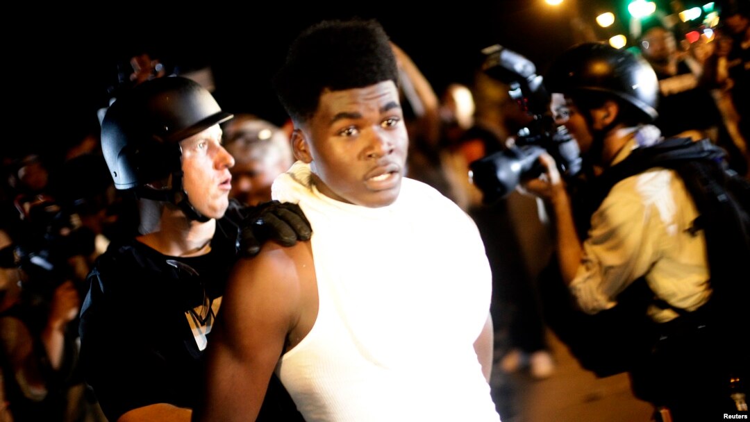 A police officer in riot gear detains a demonstrator protesting against the shooting of Michael Brown, in Ferguson, Missouri August 19, 2014. 