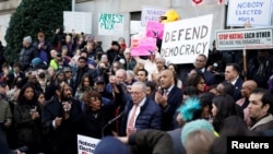 El líder de la minoría del Senado, Chuck Schumer, habla mientras la representante estadounidense Maxine Waters está junto a él, mientras manifestantes se reúnen frente al Departamento del Tesoro de EEUU en Washington el 4 de febrero de 2025.