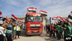 Wafanyakazi wa misaada wa Misri washerehekea kwenye kivuko cha Rafah wakati malori ya kusafirisha misaada yakianza safari kuingia Ukanda wa Gaza. Oktoba21, 2023.